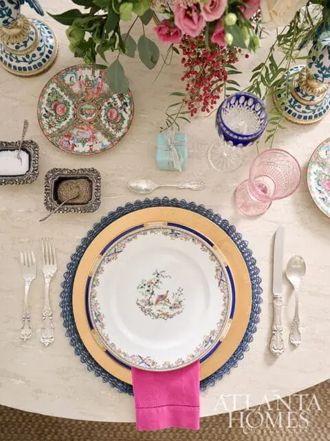 Table setting with floral plates, pink napkin, and ornate silverware.