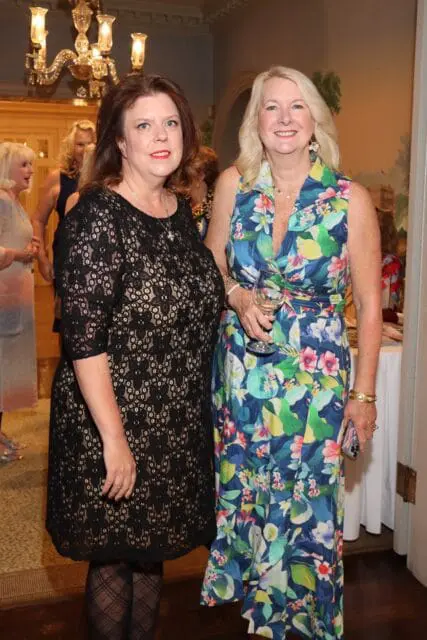 Woman in black lace dress and woman in floral dress holding wine glass
