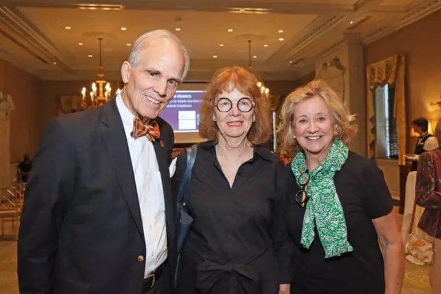 Man in suit and bow tie, woman in black shirt, woman in black shirt with green scarf