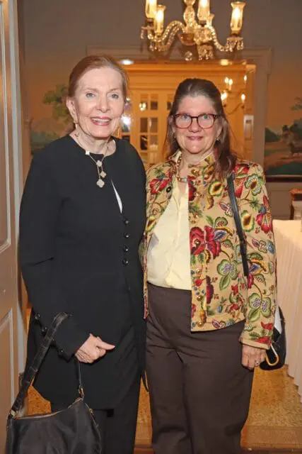 Two women smiling, one in a black jacket and the other in a floral jacket.