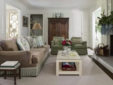 Living room with taupe sofa, green armchairs, coffee table, and stone fireplace.