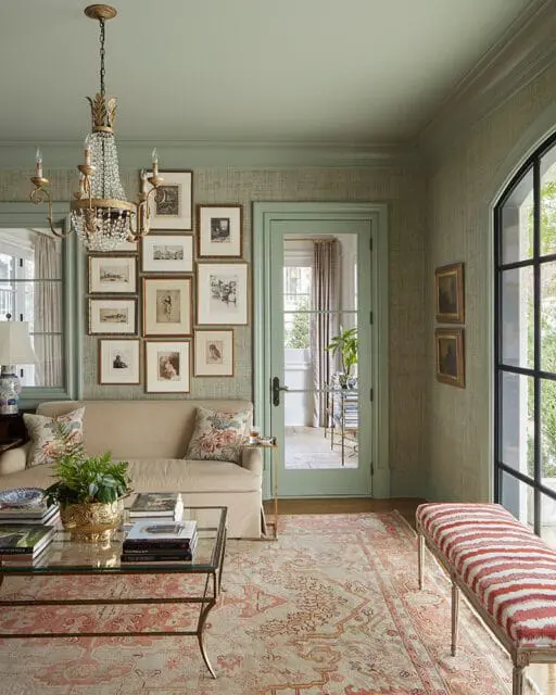 Sitting room with sage green walls, a cream sofa, gallery wall, and patterned rug.