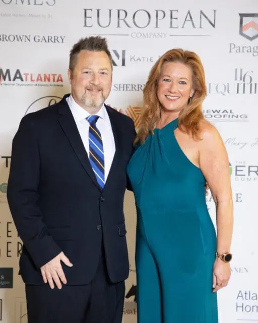 Man in a suit and blue striped tie with a woman in a teal jumpsuit