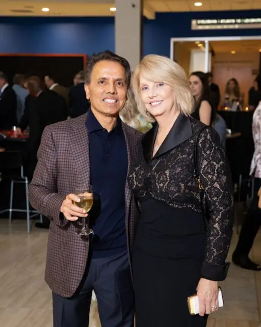 Man in plaid jacket holding wine glass, woman in black lace dress