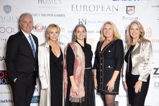 Five people pose for a photo in front of a backdrop with sponsor logos.