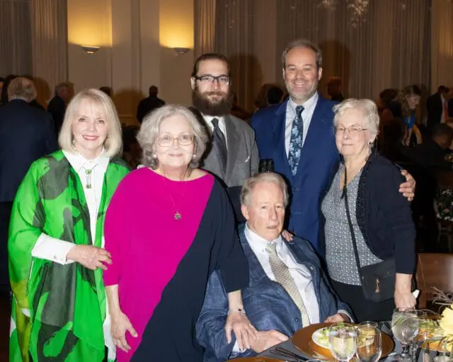 Group of six people posing for a photo at a formal event.