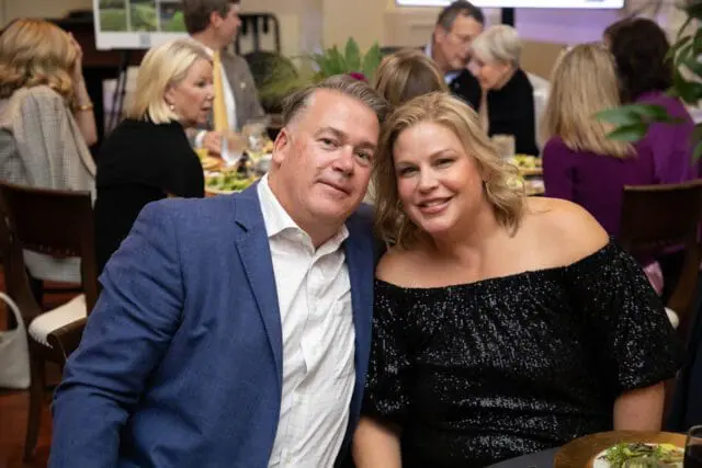 Man in blue suit and woman in black sequin dress smiling at camera