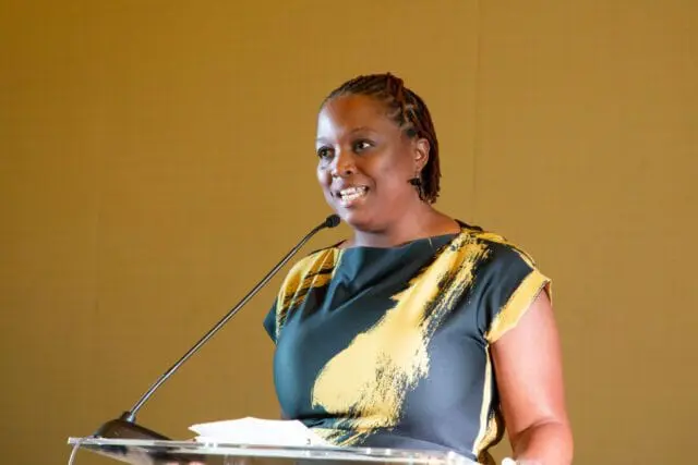 Woman with braided hair speaking at a podium.