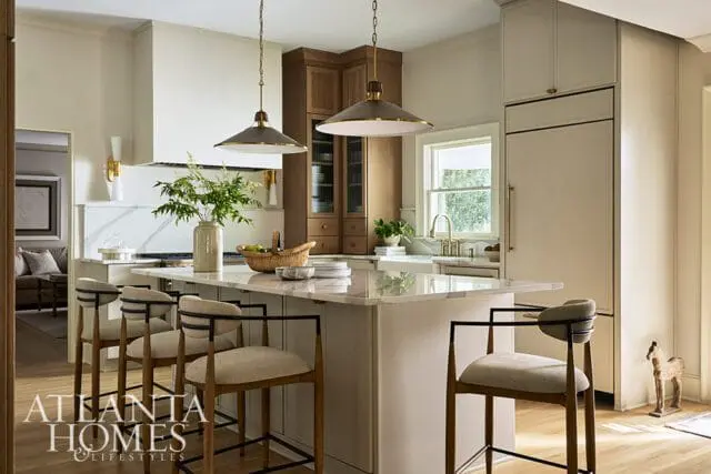 Kitchen with marble island, pendant lights, wood cabinetry, and bar stools.