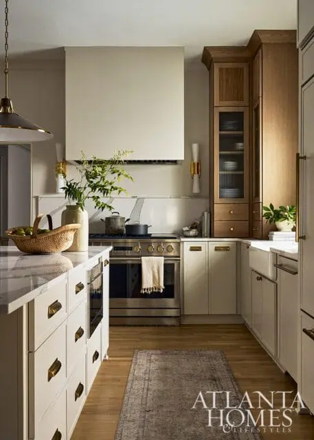 Cream kitchen with stainless steel range, marble island, and wood cabinetry. Atlanta Homes &