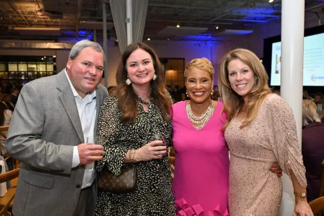Four people posing for a photo at an event.