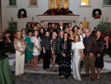 Group of people posing outside a house decorated for the holidays.