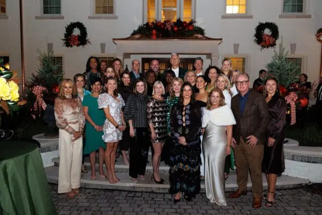 Group of people posing outside a house decorated for the holidays.
