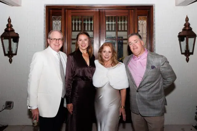 Four people posing in front of double doors.
