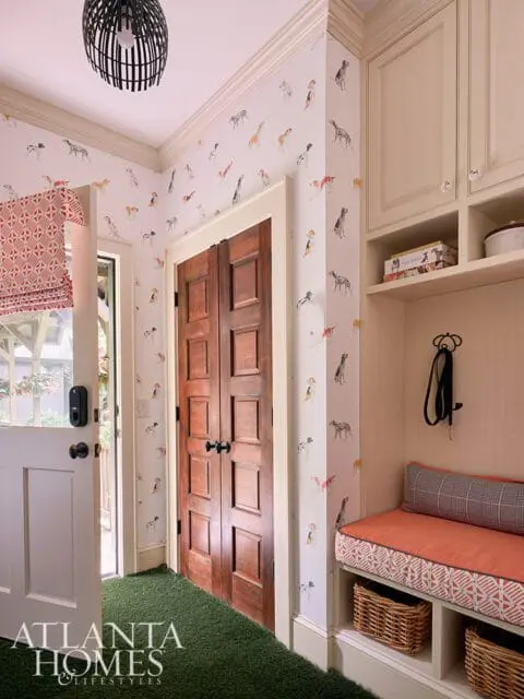 Mudroom with dog-themed wallpaper, wooden doors, and built-in bench with orange cushions.
