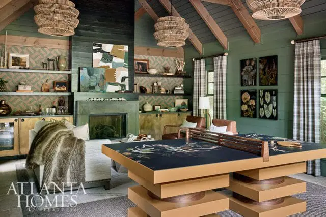 Green room with ping pong table, fireplace, and patterned wallpaper.