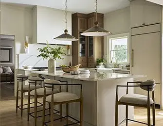 Kitchen island with marble countertop and four bar stools. Pendant lights hang above.