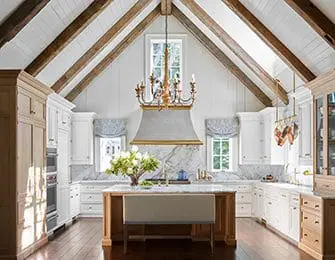 Vaulted ceiling kitchen with exposed wood beams, white cabinetry, marble backsplash, and island
