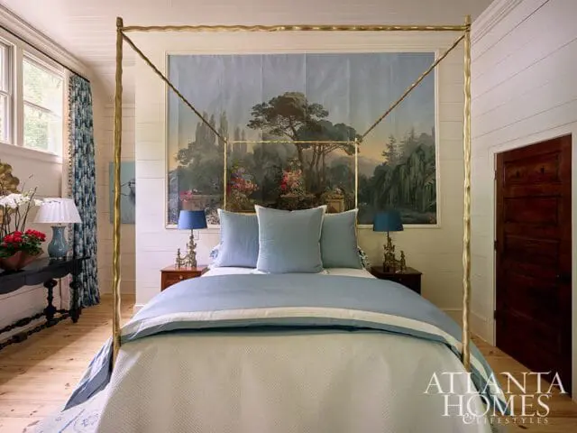 Guest bedroom with a four-poster brass bed, blue bedding, and a landscape mural.