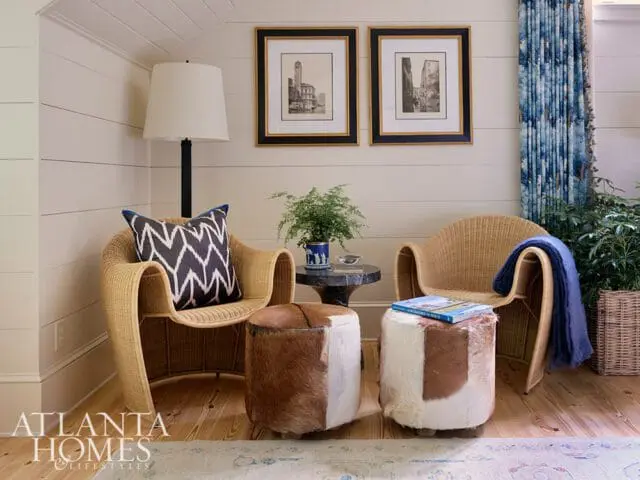 Wicker chairs with cowhide ottomans and blue patterned curtains.