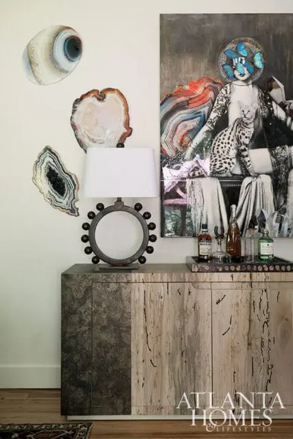 Cabinet with mixed wood and metal finishes, featuring a lamp, agate wall art, and a collage artwork.