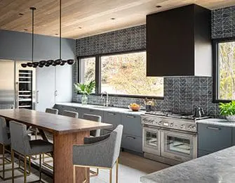 Gray kitchen with wood island, black range hood, and patterned backsplash.
