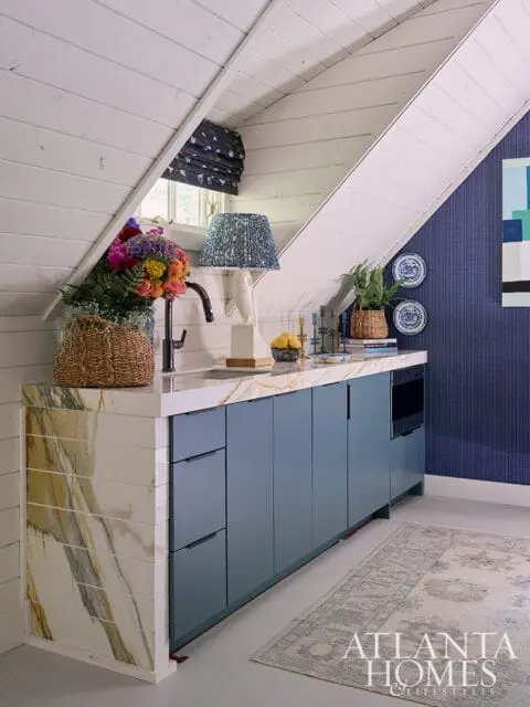 Blue cabinetry with marble countertop and backsplash, under a sloped ceiling.