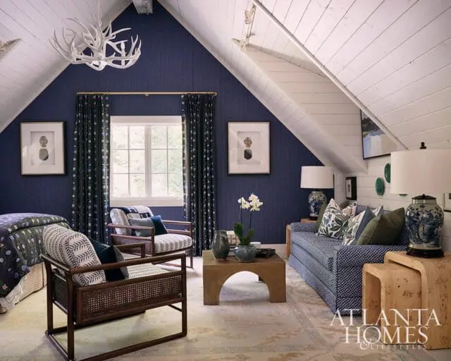 Guest suite with navy blue walls, white plank ceiling, and patterned sofa and chairs.