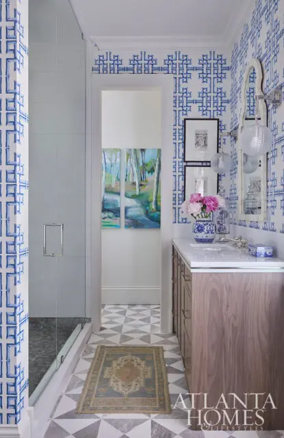 Bathroom with blue and white geometric wallpaper, wood vanity, and glass shower.