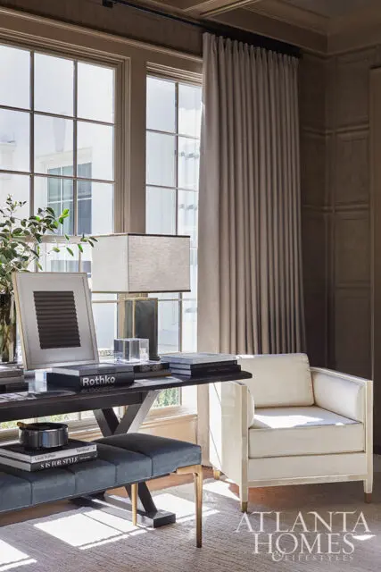 Office with a dark wood desk, blue bench, and cream armchair.