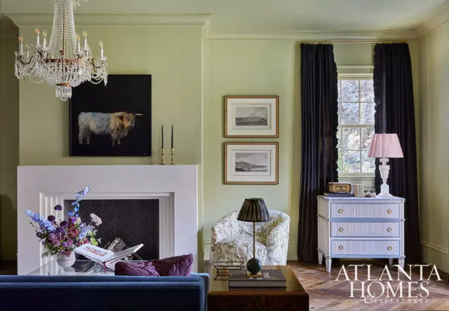 Living room with light green walls, white fireplace, and artwork of a bull.