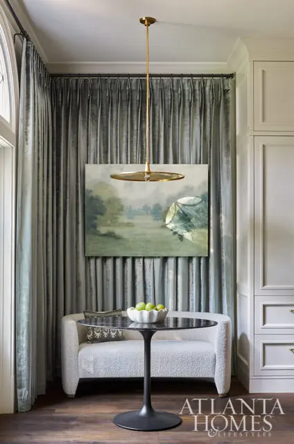Bouclé sofa with marble-top table, landscape painting, and pleated gray curtains.