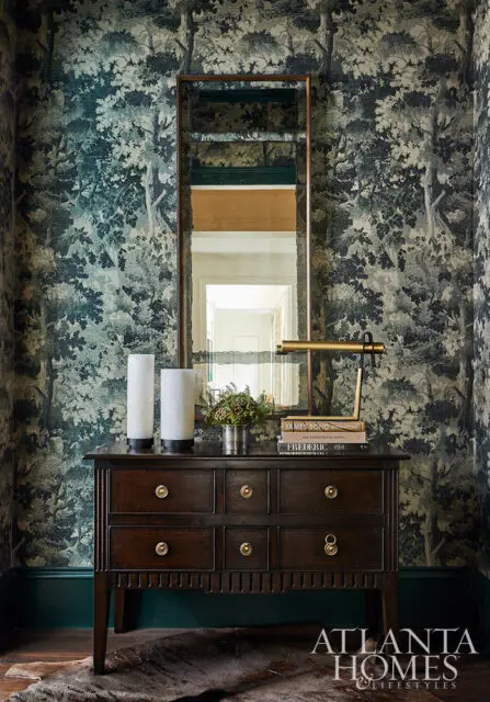 Dark wood dresser with brass hardware against forest-themed wallpaper