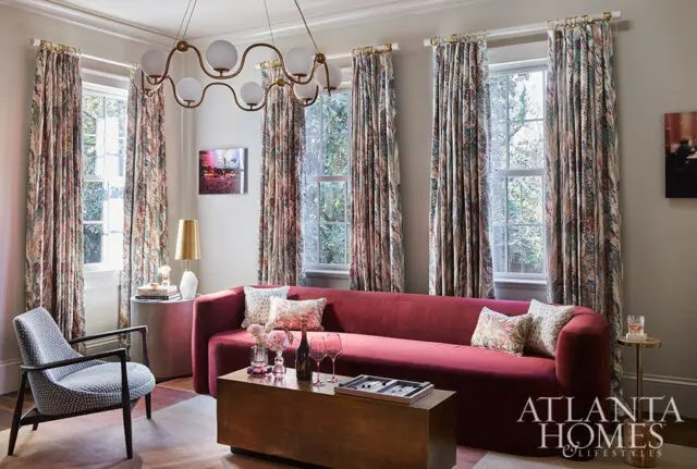 Living room with red sofa, patterned curtains, and a modern chandelier.