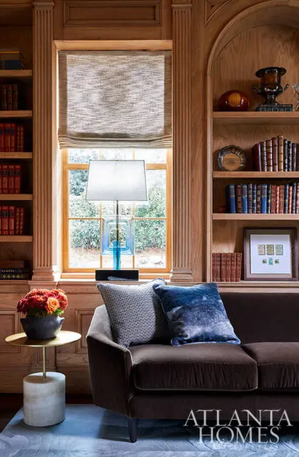 Brown velvet sofa with blue and patterned pillows, next to a side table with flowers.