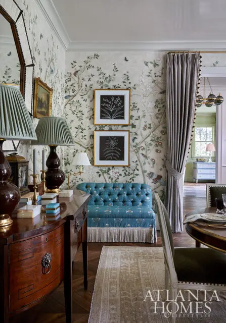 Dining room with floral wallpaper, teal tufted bench, and dark wood console table.