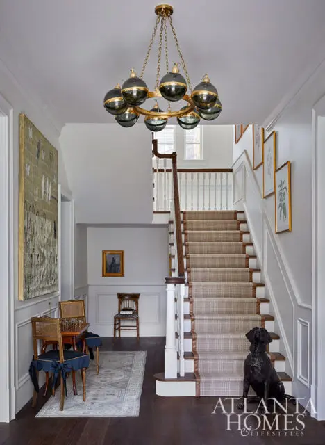 Foyer with plaid carpeted stairs, large abstract art, and a dog statue