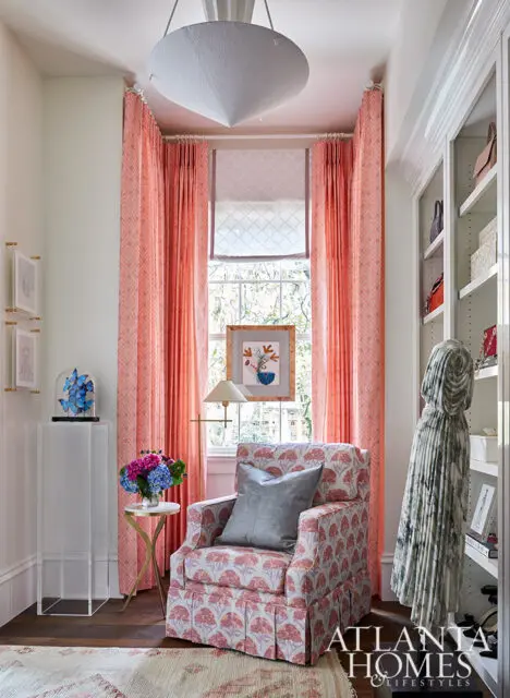 Living room with coral patterned curtains, floral armchair, and built-in shelving.