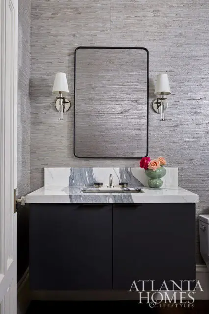 Powder room vanity with dark cabinets, marble countertop, and textured silver wallpaper.