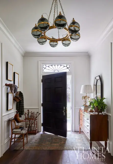 Foyer with black door, oriental rug, wooden dresser, and globe chandelier