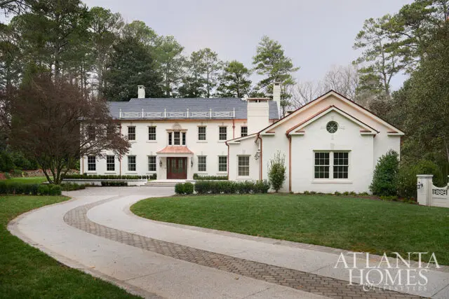 White brick house with copper accents, circular window, and winding driveway