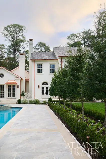 White brick house with copper gutters, arched doorway, and swimming pool