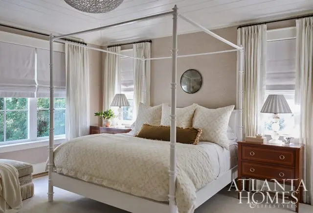 Bedroom with white four-poster bed, textured wallpaper, and patterned bedding.