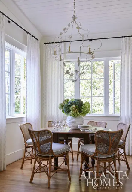 Dining room with round wood table, wicker chairs, and floral chandelier