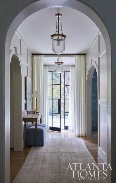 Hallway with arched doorways, glass pendant lights, and French doors leading outside.