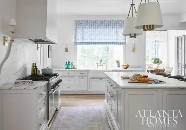White kitchen with marble countertops, gray cabinets, and a blue patterned window shade.