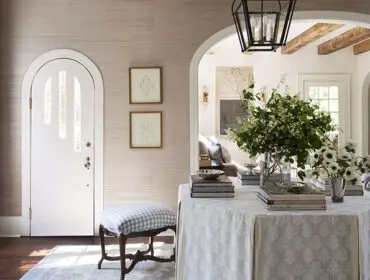 Foyer with arched doorway, textured wallpaper, and a round table with floral tablecloth.