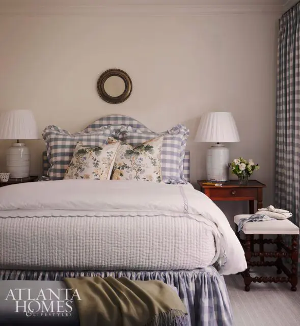 Bedroom with gingham headboard, white quilted bedspread, and floral accent pillows.