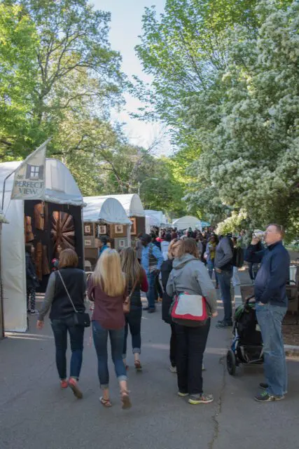 Outdoor art festival with white tents and blooming trees