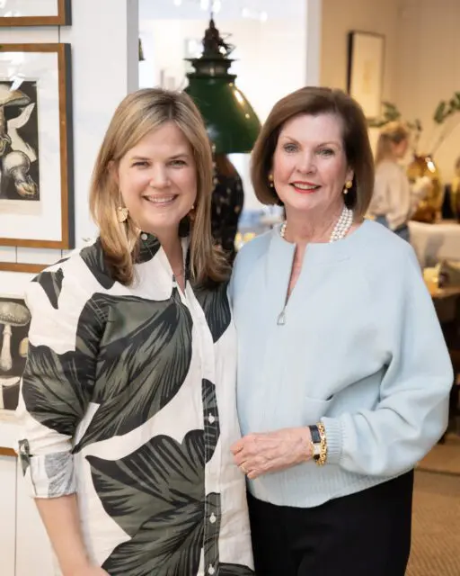Two women smiling, one in a leaf-print shirt, the other in a light blue sweater.